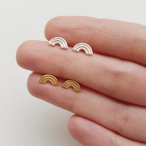 May include: Two pairs of rainbow-shaped earrings. One pair is silver and the other pair is gold.