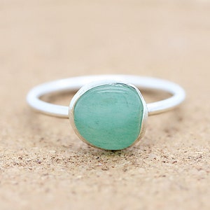 May include: A silver ring with a light blue, oval-shaped gemstone.