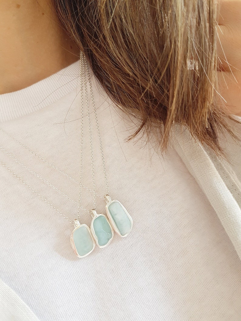 May include: Four silver necklaces with light blue aquamarine stone pendants. The pendants are rectangular and have a natural, irregular shape.