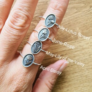 Pu&ograve; includere: Cinque anelli d'argento con diversi disegni di fiori. Ogni anello &egrave; etichettato con un mese e un nome di fiore: aprile-margherita, maggio-mughetto, giugno-rosa, luglio-fiore di loto.
