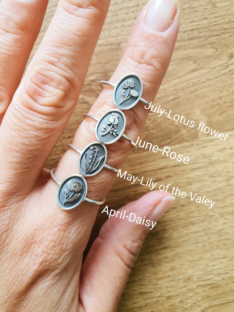 Pu&ograve; includere: Cinque anelli d'argento con diversi disegni di fiori. Ogni anello &egrave; etichettato con un mese e un nome di fiore: aprile-margherita, maggio-mughetto, giugno-rosa, luglio-fiore di loto.