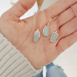May include: Three delicate necklaces with light blue stone pendants set in rose gold. The stones are irregular in shape and have a smooth, polished finish.