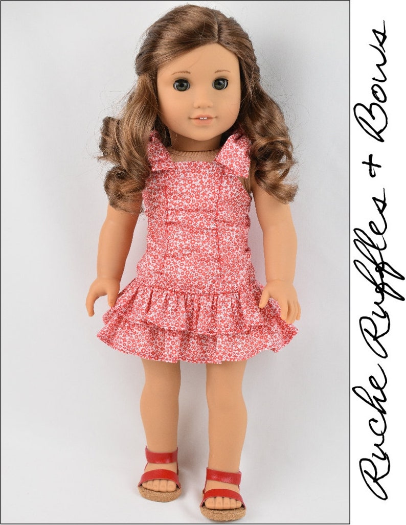 May include: A red and white floral print dress with ruffles and bows. The dress is worn by a doll with brown hair and brown eyes.