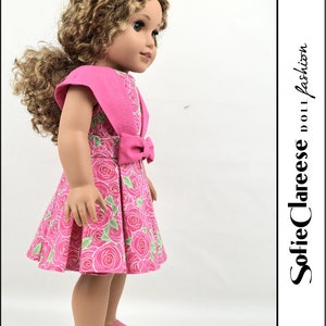 May include: A pink dress with a floral print and a matching pink bow. The dress has short sleeves and a full skirt. The doll is wearing pink sandals.