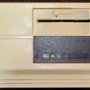 May include: A vintage Hyundai computer. The beige-colored computer has a floppy disk drive, a dark gray section with indicator lights, and the brand name "HYUNDAI" printed on the top left.