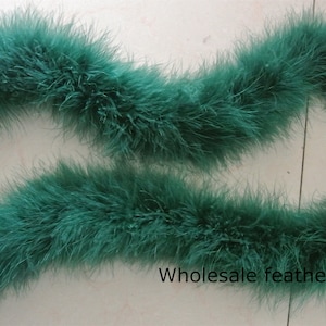 Pode incluir: Uma longa fita de boa de penas verde-azulada. A boa é macia e fofa, e é perfeita para adicionar um toque de glamour a qualquer roupa.