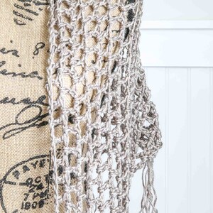May include: A silver crochet shawl with a delicate openwork pattern and fringe trim. The shawl is draped over a mannequin.