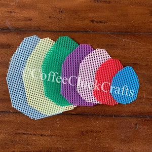 May include: Seven different colored plastic canvas circles, ranging in size from small to large. The colors are light blue, light yellow, green, purple, pink, red, and blue.