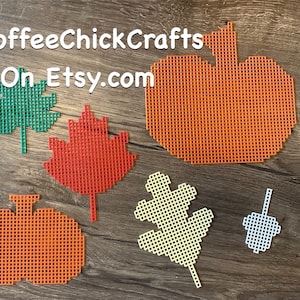 May include: Various fall-themed plastic canvas cutouts, including pumpkins, maple leaves, oak leaves, and an acorn. The cutouts are in shades of orange, red, green, and white. The Etsy shop name, CoffeeChickCrafts, is visible in the image.