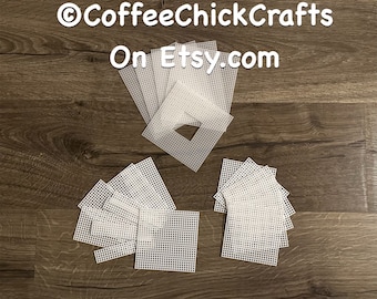May include: A set of 15 white plastic canvas squares, perfect for cross-stitch or needlepoint projects. The squares are arranged in three groups, with one group featuring a larger square with a central opening.