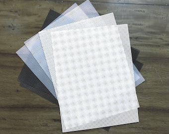May include: A set of four plastic canvas sheets in black, white, gray, and light gray. The sheets are square and have a grid pattern.