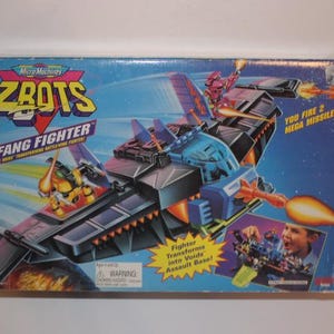 May include: A vintage Micro Machines ZROTS Fang Fighter toy box. The box features a futuristic fighter jet design in shades of blue, gray, and orange, with the text "YOU FIRE 2 MEGA MISSILES!" and "Fighter Transforms into Void Assault Base!"