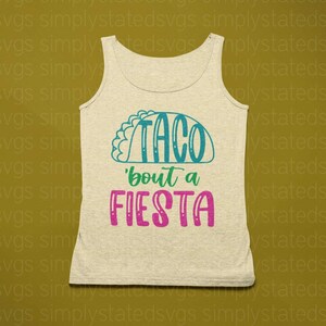 May include: A beige tank top with the text "Taco 'bout a Fiesta" in teal and pink lettering. The text is stylized to look like a taco.