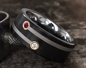 Puede incluir: Un anillo negro con dos bandas plateadas y tres piedras preciosas. El anillo tiene una piedra preciosa rosa y dos piedras preciosas blancas más pequeñas.