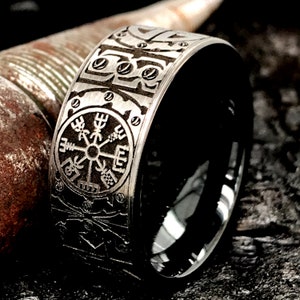 Peut inclure: Une bague en acier inoxydable noir et argent avec un motif grav&eacute; d&eacute;taill&eacute;. La bague pr&eacute;sente une boussole avec un symbole nordique au centre.