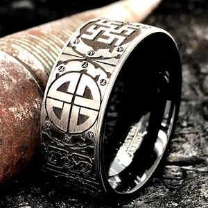 Peut inclure: Une bague en carbure de tungst&egrave;ne noire avec une bande argent&eacute;e orn&eacute;e d'un motif complexe de n&oelig;uds et de symboles celtiques. La bague est grav&eacute;e des mots "Tungsten Carbide".