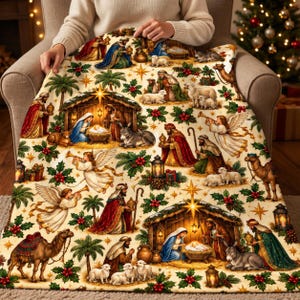 May include: A cream-colored throw blanket featuring a repeating pattern of the Nativity scene, including figures of the Holy Family, angels, shepherds, camels, and donkeys, interspersed with green holly leaves, red berries, and gold stars.