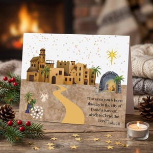 May include: A Christmas card featuring a watercolor illustration of a town with a path leading to a stable. The card includes the text "For unto you is born this day in the city of David a Saviour, which is Christ the Lord." Luke 2:11.