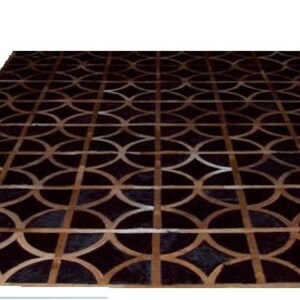 May include: A black and brown leather rug with a geometric pattern of overlapping circles. The rug has a modern design and would be a stylish addition to any home.