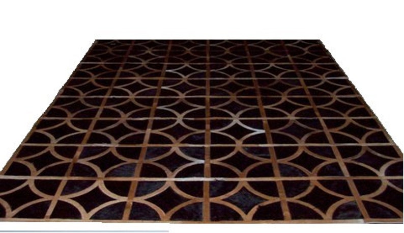 May include: A black and brown leather rug with a geometric pattern of overlapping circles. The rug has a modern design and would be a stylish addition to any home.