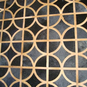 May include: A black and tan geometric patterned rug with a repeating circular design.