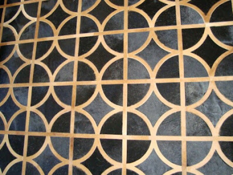 May include: A black and tan geometric patterned rug with a repeating circular design.