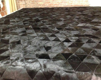 Può includere: Tappeto in pelle di mucca nero e bianco con un motivo geometrico di triangoli. Il tappeto è realizzato in pelle naturale e ha una sensazione morbida e lussuosa.