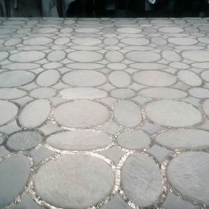 May include: A white surface with a pattern of overlapping circles, each with a silver outline. The circles are arranged in a random pattern, creating a unique and modern design.