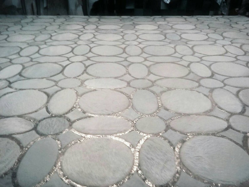 May include: A white surface with a pattern of overlapping circles, each with a silver outline. The circles are arranged in a random pattern, creating a unique and modern design.