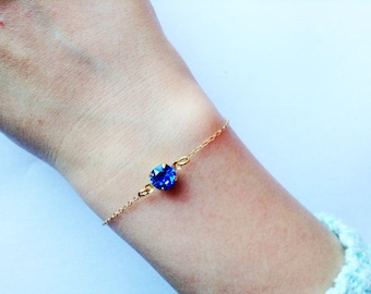 Peut inclure: Un bracelet en chaîne dorée avec un seul strass bleu.