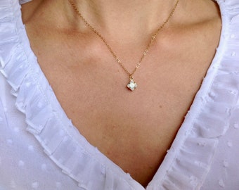 May include: A gold chain necklace with a small white flower pendant.