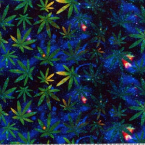 May include: Fabric with a repeating pattern of green cannabis leaves on a dark blue background with a galaxy-like effect. The leaves have yellow and green gradients. The image includes a ruler at the bottom, with measurements in inches.