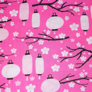 May include: Bright pink fabric with a repeating pattern of white Japanese lanterns, cherry blossoms, and black branches. The lanterns are in various shapes and sizes, with a striped design. The blossoms are small and white.