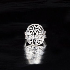 K&ouml;nnte beinhalten: Ein silberner Ring mit einem runden Design mit filigranen Ausschnitten. Das Design erinnert an einen Baum mit &Auml;sten und Bl&auml;ttern.
