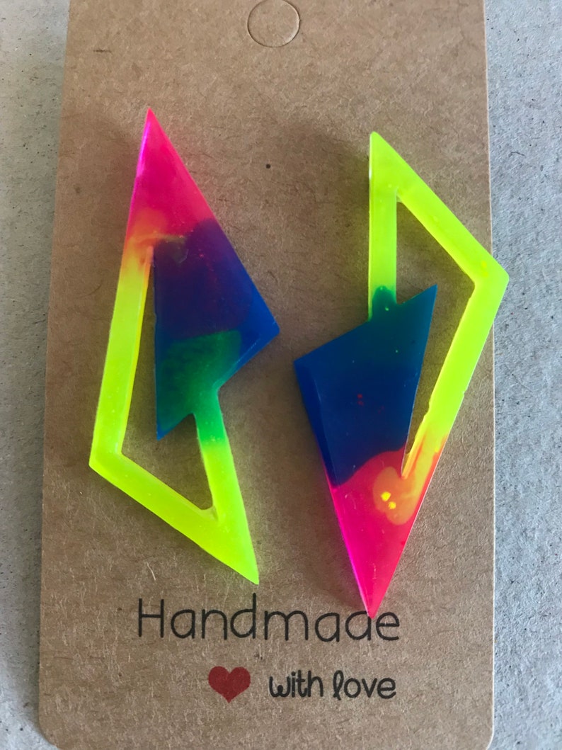 Puede incluir: Un par de pendientes geom&eacute;tricos de color amarillo ne&oacute;n y rosa con un dise&ntilde;o de remolino arco&iacute;ris. Los pendientes est&aacute;n hechos a mano con amor.