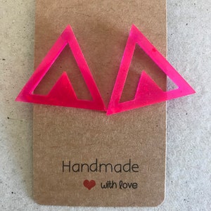 May include: A pair of pink triangle shaped earrings with a smaller triangle cut out in the center. The earrings are handmade with love.
