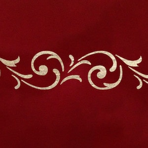 Può includere: Un bordo decorativo bianco con un motivo ripetitivo di volute e foglie stilizzate su uno sfondo rosso.