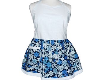 May include: A white apron with a blue and white snowflake print. The apron has a halter neck strap and a single pocket.
