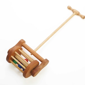Classic toddler push toy is 24" long and is made entirely of alder wood. Six rainbow colored wooden balls  tumble in a cylinder-shaped cage when toy is pushed. The toy has a beautiful wood-turned handle that's easy for toddlers to grasp.