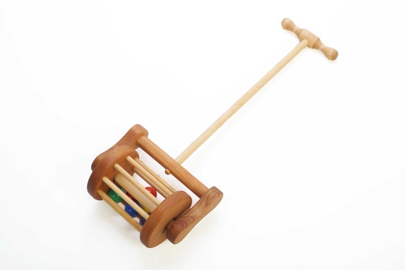 Classic toddler push toy is 24" long and is made entirely of alder wood. Six rainbow colored wooden balls  tumble in a cylinder-shaped cage when toy is pushed. The toy has a beautiful wood-turned handle that's easy for toddlers to grasp.