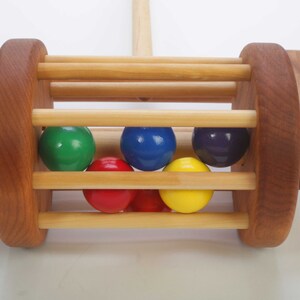 Close up picture of the red, orange, yellow, green, blue and purple wooden balls that make a pleasant sound when bouncing around in the wooden cylinder- shaped cage.