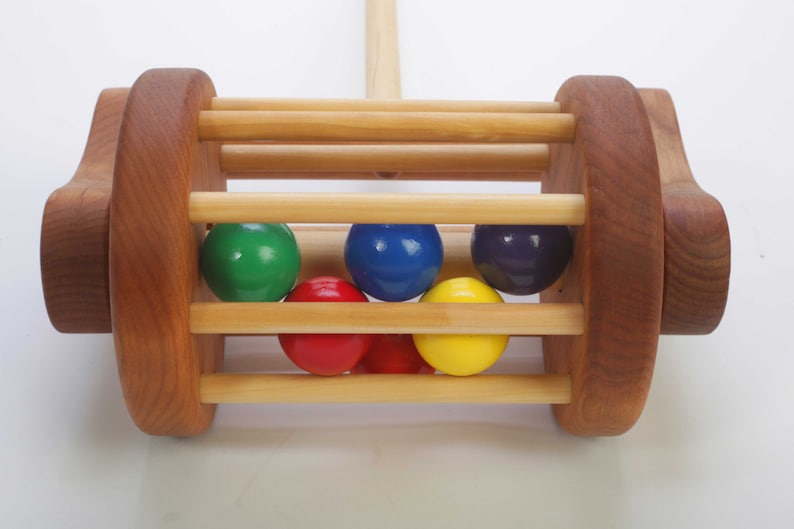 Close up picture of the red, orange, yellow, green, blue and purple wooden balls that make a pleasant sound when bouncing around in the wooden cylinder- shaped cage.