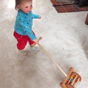 Handmade wooden lawnmower push toy for toddlers. Toddlers can also move the toy back and forth to pretend to vacuum. Sturdy construction includes a beautiful wood turned handle easily grasped with two hands to aid in learning to walk.