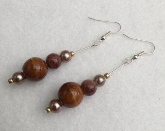May include: A pair of dangle earrings with brown and pink beads and silver hooks.