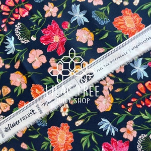 May include: A navy blue fabric with a floral print featuring pink, red, and orange flowers. The fabric has a white border with the text "The Flower Fields" and "Main Street Quilt Shop" printed on it. The text "Feel the Difference | artgalleryfabrics.com" is also printed on the border.