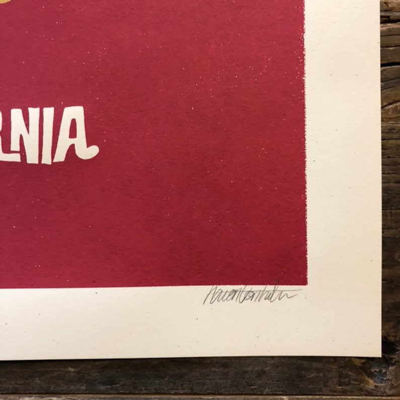 Pu&ograve; includere: Un poster rosso con la parola "CALIFORNIA" in lettere gialle. Il poster &egrave; firmato in basso a destra con il nome "Aaron " seguito da una firma illeggibile.