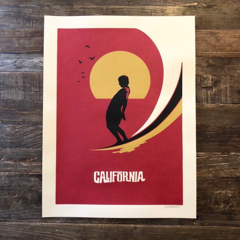 Pu&ograve; includere: Un poster rosso e oro con la silhouette di una persona che fa surf su un'onda. Il sole sta tramontando sullo sfondo e ci sono uccelli che volano nel cielo. Il testo "CALIFORNIA" &egrave; stampato nella parte inferiore del poster.