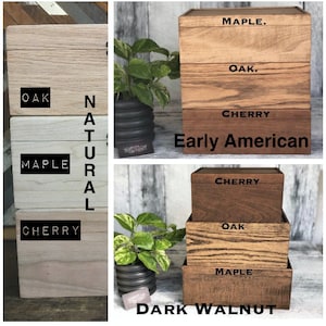 May include: Three wooden boxes stacked on top of each other, showing different wood stains. The top box is labeled "Maple", the middle box is labeled "Oak", and the bottom box is labeled "Cherry". The boxes are labeled "Early American".