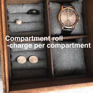 Pode incluir: Uma caixa de madeira com compartimentos para guardar joias e outros objetos pequenos. A caixa tem um forro de feltro cinza e é dividida em quatro seções. Os compartimentos estão etiquetados "Compartment roll - charge per compartment".
