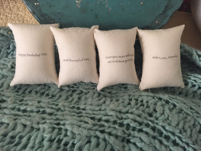 Puede incluir: Cuatro peque&ntilde;as fundas de almohada blancas con diferentes mensajes bordados. Los mensajes son "Happy Birthday! 2016", "Until the end of time.", "I love you more with each second that goes by" y "With Love, Amanda".
